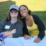 Participant Erin pictured smiling with TNS Staff member Maya at the 2025 Community Programming event for Adam's Way.